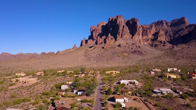 Aerial shot flying over houses panning up to see the north end of the Superstition Mountains in Apache Junction Arizona.