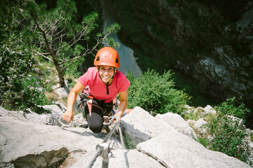 Young happy woman who is climbing along a via ferrata
