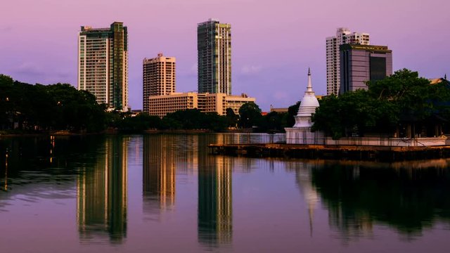 Sri Lanka. View of Beira Lake in Colombo, Sri Lanka with buddhist temple and illuminated modern buildings at sunrise. Night to day time-lapse. Clear sky, zoom in