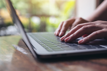Closeup image of hands using and typing on laptop keyboard on wooden table