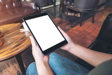 Mockup image of woman's hands holding black tablet pc with blank desktop screen while sitting in cafe
