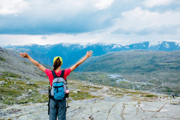 Sportive girl hiker going up the mountain. Back view of woman stand feel freedom with arms stretched to the sky enjoying the scenery in the Norway. Adventure, travel, leave your comfort zone concept.