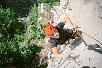 young man who is climbing along a via ferrata