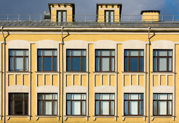 The facade of the old building with yellow walls and white décor on the windows