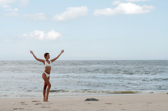 Beautiful tanned woman in bikini enjoying a walk on the beach