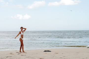 Fototapeta na wymiar Beautiful tanned woman in bikini enjoying a walk on the beach