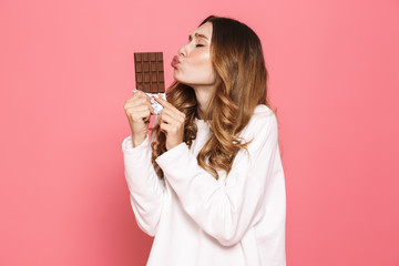 Portrait of a happy young woman kissing chocolate bar