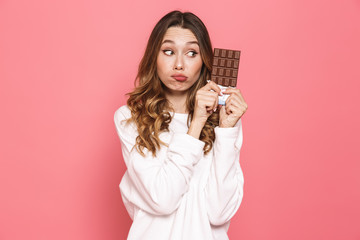Portrait of a pensive young woman holding chocolate bar