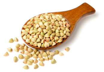 uncooked buckwheat in the wooden spoon, isolated on the white background.