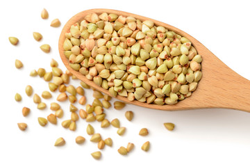 uncooked buckwheat in the wooden spoon, isolated on the white background, top view