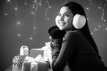 The beauty lady is wearing sweater,put earing to cover her ear,wear black glove,plenty of gift box on desk,black and white tone,