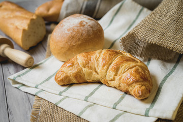 fresh bread and wheat on sack and wooden table.
