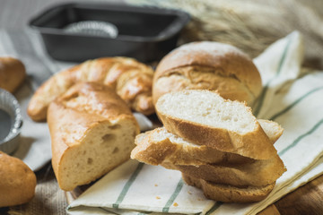 fresh bread and wheat on sack and wooden table.