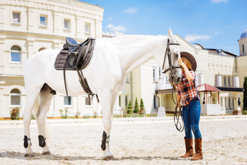 Kissing horse. Caring loving cowboy girl fond of equestrianism kissing her beautiful white racing...