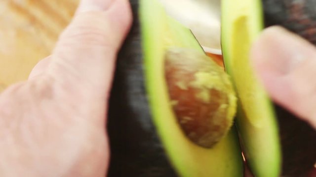 A woman scoops the flesh of an avocado with a large spoon