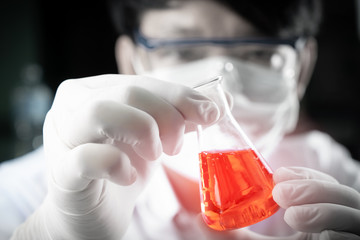Student boy holding erlenmeyer flask chemistry equipment with red liquid benzene oil energy in...