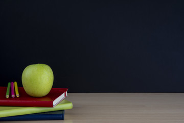 manzana en libros con lápices y pizarra vacía, regreso a la escuela