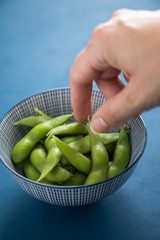 Frau isst Portion grüne, japanische Edamame Sojabohnen in Porzellan Schale