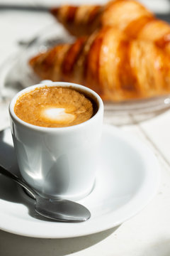 Hot coffee and croissant breakfast in a sunny morning, natural light.