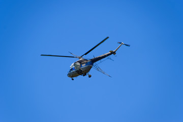 Fototapeta na wymiar A helicopter of agricultural aviation is flying in the blue sky.