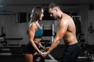 Fototapeta na wymiar Man instructor and woman train, lifting dumbbells