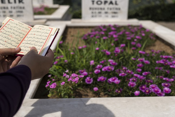 read a Koran ,holy book for Muslims on the cemetery visit to the festival. 