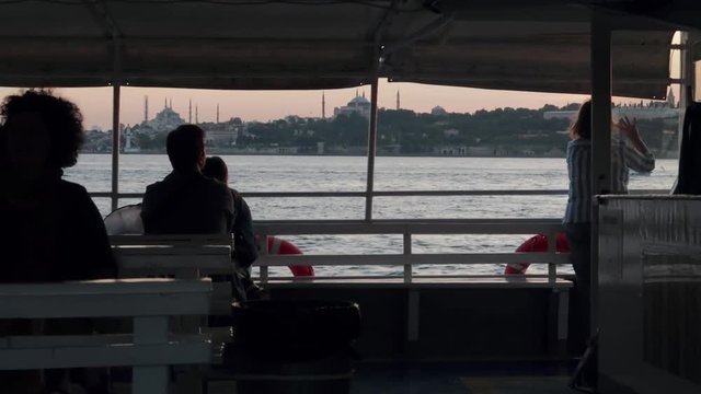 Passengers enjoying bumpy ferry ride from Europe to Asia across Istanbul's Bosphorus during sunset (slow motion)