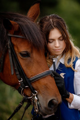 Fototapeta premium Young woman rider hugging with brown horse, eyes closed. Concept friends