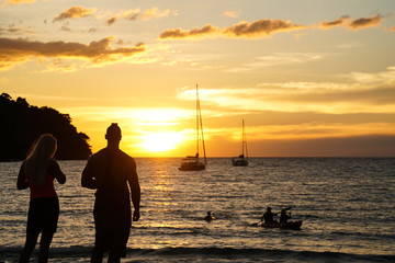 Fototapeta premium a couple stand watch sunset take photo by the beach