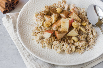 Oatmeal with fresh apples, nuts and cinnamon for Breakfast on the table, close-up, horizontal