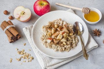 Oatmeal with fresh apples, nuts and cinnamon for Breakfast on the table, close-up, horizontal