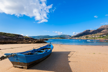 Fishing boat on the beach with blue sky background.