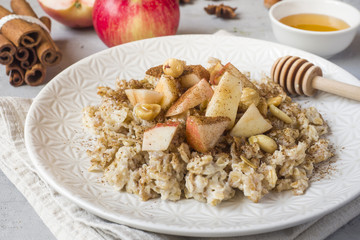 Oatmeal with fresh apples, nuts and cinnamon for Breakfast on the table, close-up, horizontal