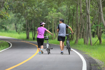 Middle aged couple relaxing exercise with bicycle in park