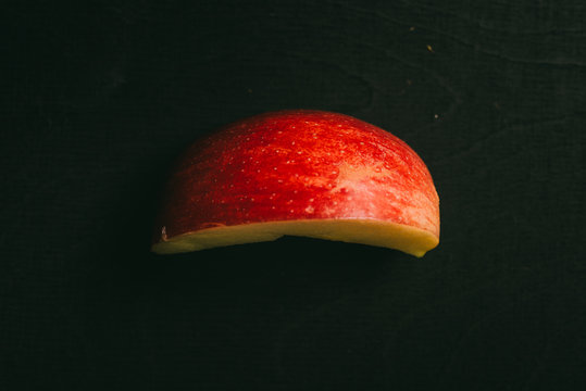 Cut apple lying on black table in background with blank space as flat lay