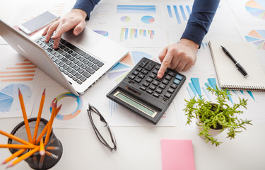 Businessman holding a pen is working with graph documents and sunset light background. Stock market chart and finger pointing on tablet in office.