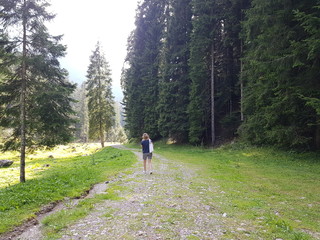 Passeggiata in un sentiero di montagna. Ragazza bionda con una borsa bianca da sola