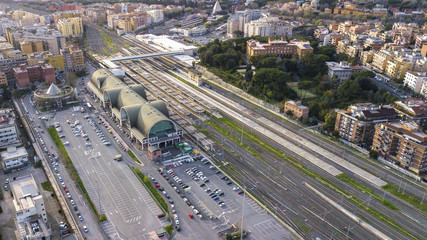 Aerial view of the Ostiense station in Rome, Italy. There are many tracks, rails and tourists passing by the station. At the bottom we see the Cestia Pyramid.