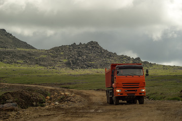 Naklejka premium dump truck rides on the mountain road under construction