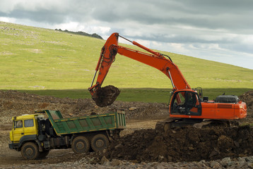 laying a road in a mountainous area, an excavator and a dumper during construction work