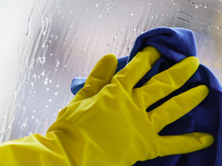 Gloved hand cleaning window rag and spray