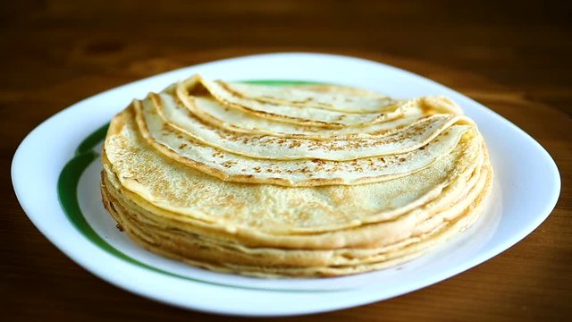 Thin pancakes stacked on a plate in a pile