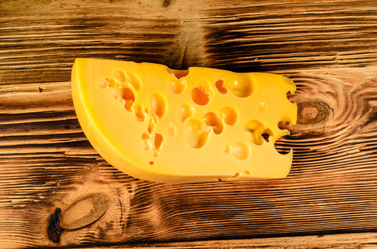 Piece of cheese on wooden table. Top view