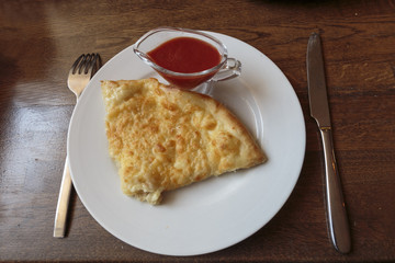 Slice of tasty cheese pizza on a white plate in a restaurant, Italian traditional appetizer.