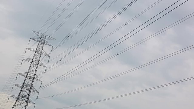 High voltage transmission lines with clouds in the background.