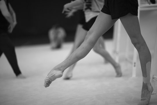 Legs of gymnasts in choreographic movements in a rehearsal room during training