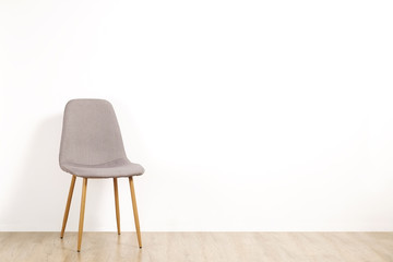 Single elegant gray loft style chair standing alone on wooden floor in empty room, big blank wall background. Large copy space for text. Only one vacant seat. Human resources hiring campaign concept.