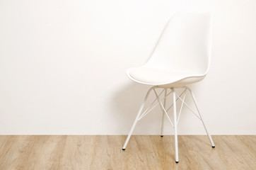 Single elegant white loft style chair standing alone on wooden floor in empty room, big blank wall background. Large copy space for text. Only one vacant seat. Human resources hiring campaign concept.