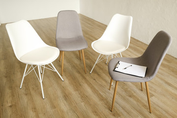 Multiple loft style empty chairs standing in row on wooden floor, counselor's seat clipboard & pen...
