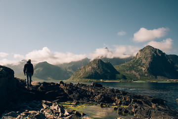 Man walking by the shore overlooking mountains